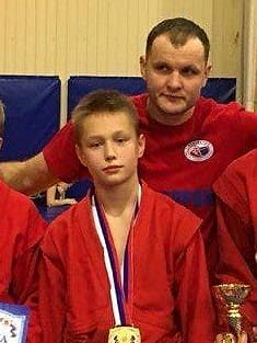 Даниил Викторов с золотой медалью, за ним тренер Павел Копейкин