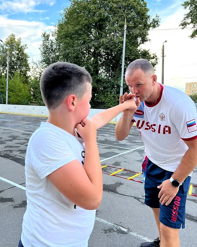 Тренер ставит мальчику удар и защиту
